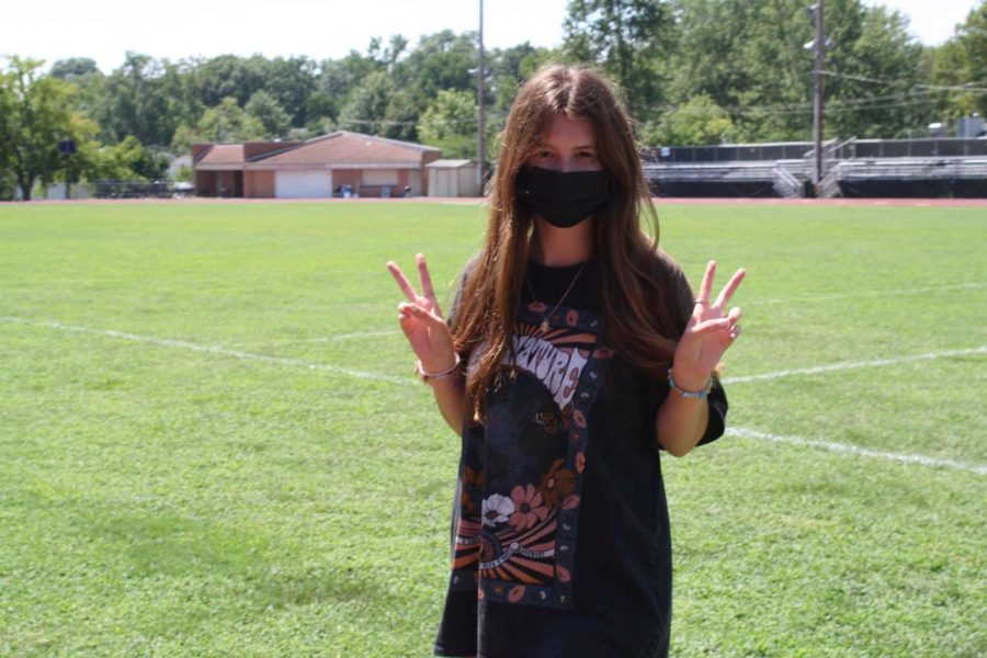 Emelda+Forney+poses+for+the+camera+on+the+football+field+holding+up+two+peace+signs+with+her+fingers.
