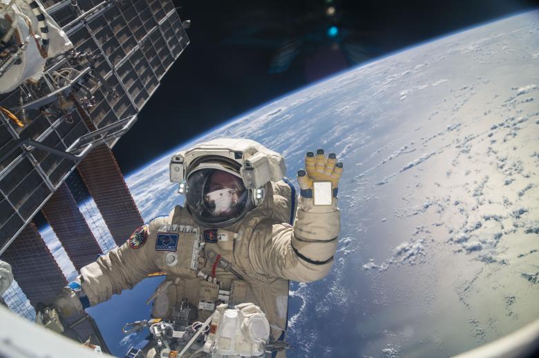 An+astronaut+waves+to+the+camera+as+he+works+on+the+International+Space+Station.