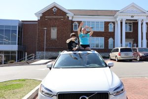 Haylie Minshall and Max Pulliam hang outside of car window for their senior superlative Best on Aux.