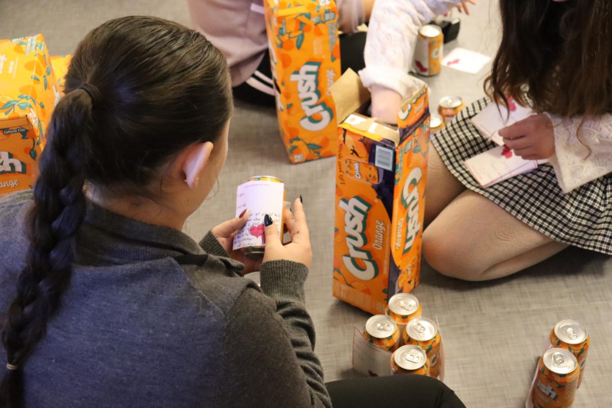 Norah Woodman (12) helps her fellow Student Council members by labeling a Crush can.