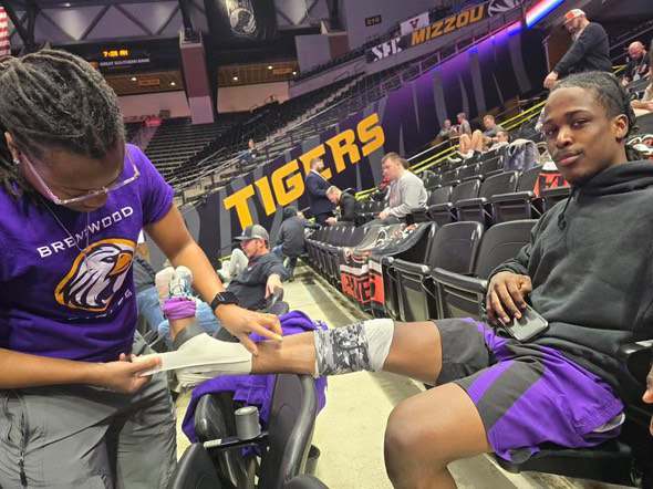 Senior Jesse Lane smiles as he's getting patched up by Brentwood's trainer, Dee, at state. 